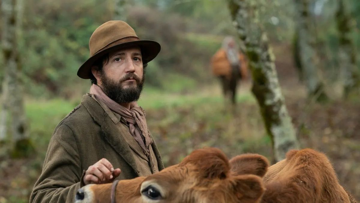 John Magaro porte un costume du nord-ouest du Pacifique du XIXe siècle tout en caressant une vache très douce dans First Cow.