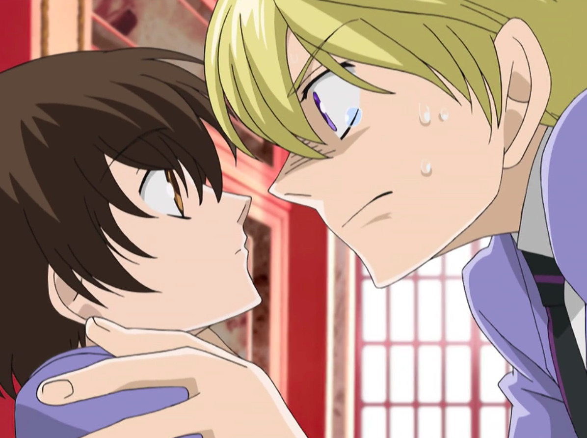 Personnages du Ouran High School Host Club – Tamaki, à droite, saisit Haruhi par les épaules.  Elle a l'air imperturbable mais le regarde à nouveau.  Son expression est intense.