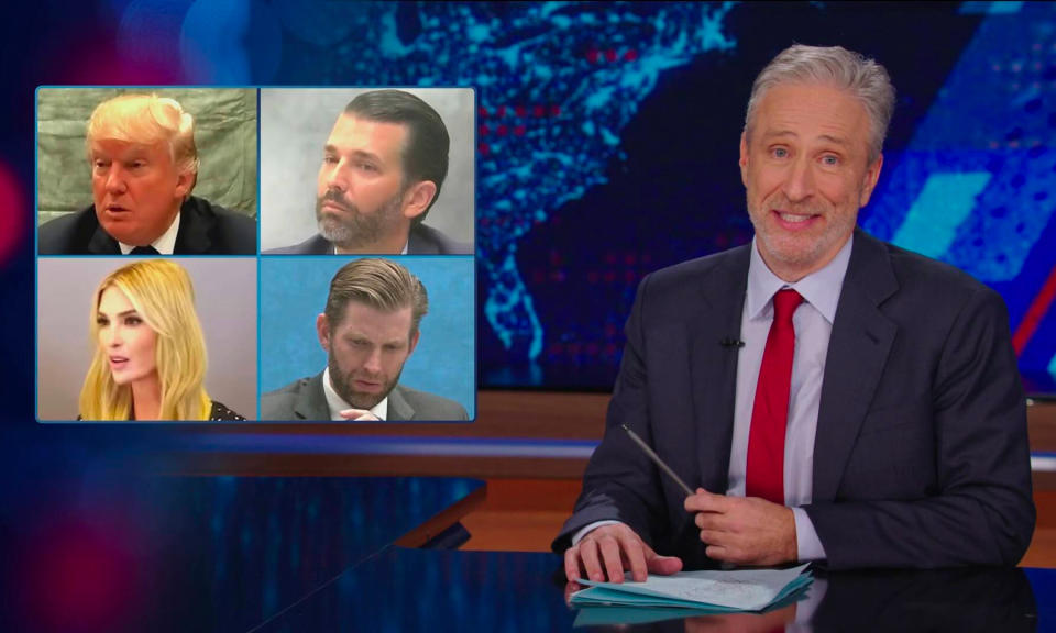 Image toujours du retour de Jon Stewart en 2024 au Daily Show.  L'animateur est assis à un bureau avec une superposition montrant des photos de Donald Trump et de ses enfants.