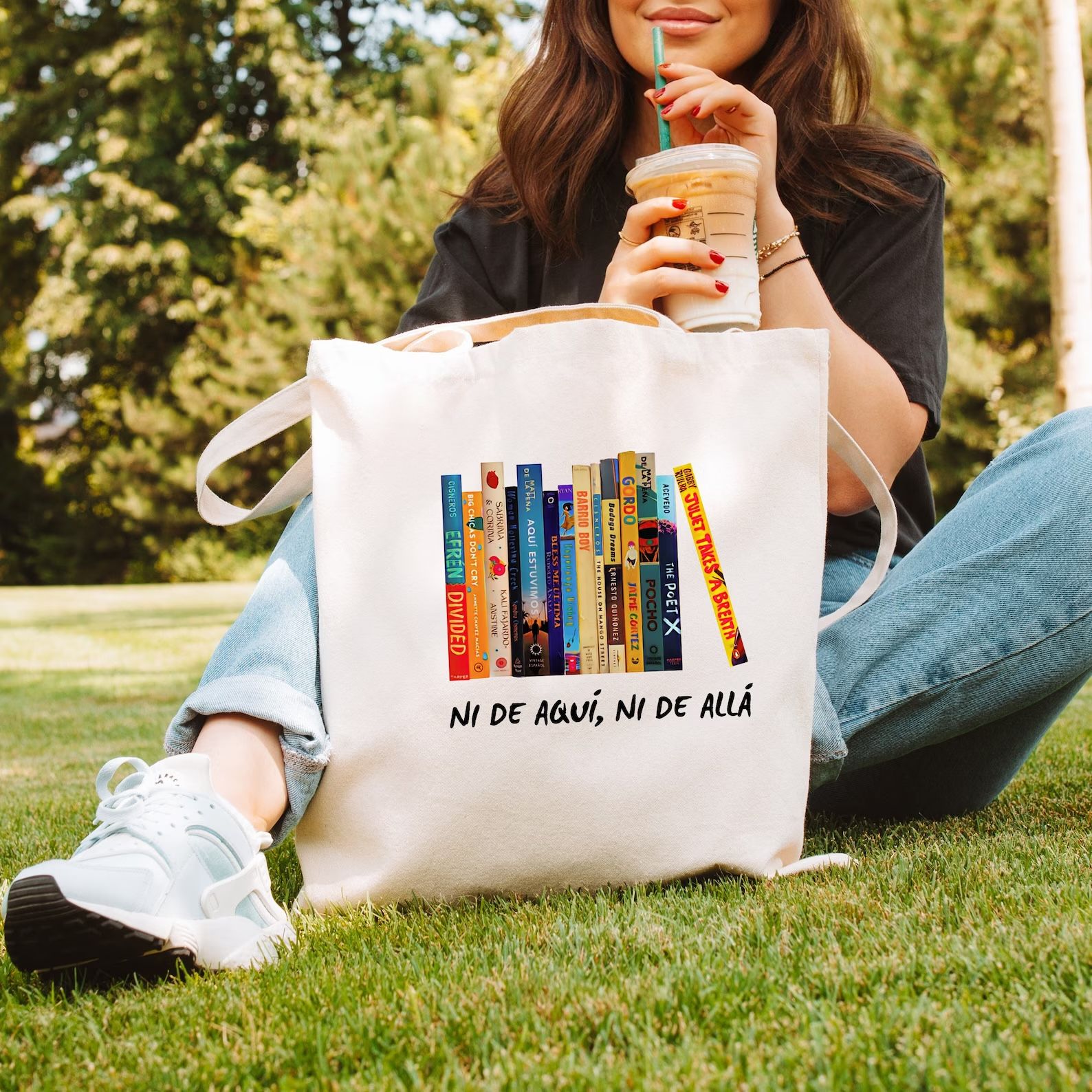 sac fourre-tout en toile avec un motif de dos de livres colorés.  Sous les livres se trouvent les mots "ni de aqui, ni de alla"