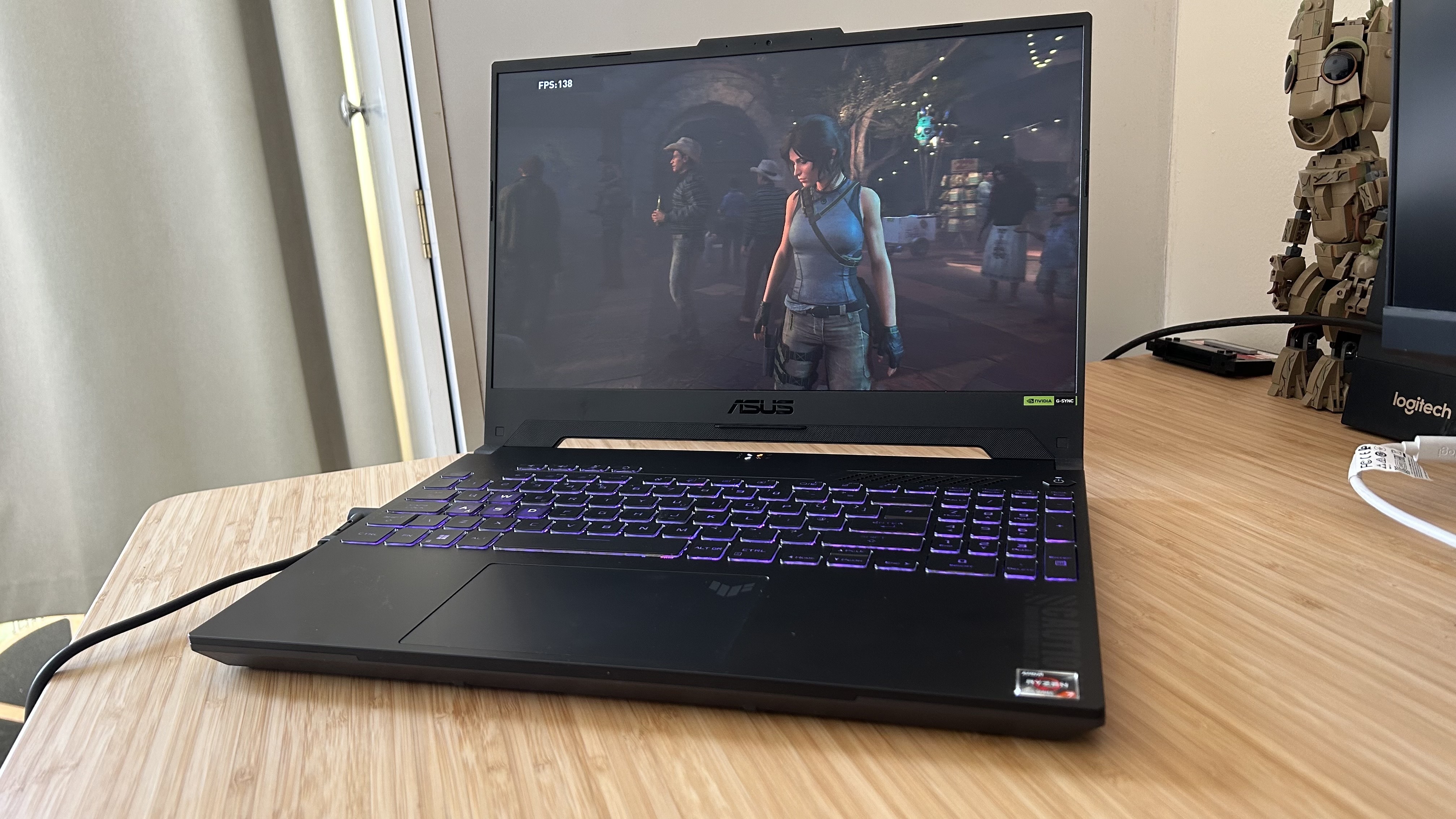 Ordinateur portable de jeu Asus TUF A15 ouvert sur un bureau en bois et jouant à Shadow of the Tomb Raider