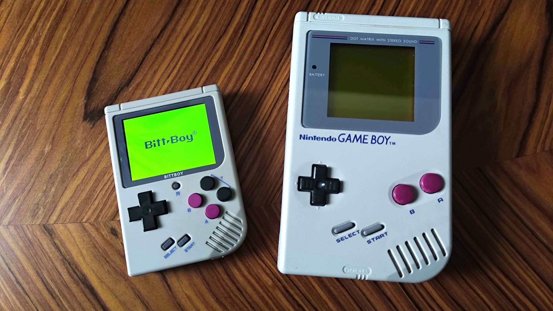 Bittboy à côté du Gameboy original sur une table en similibois