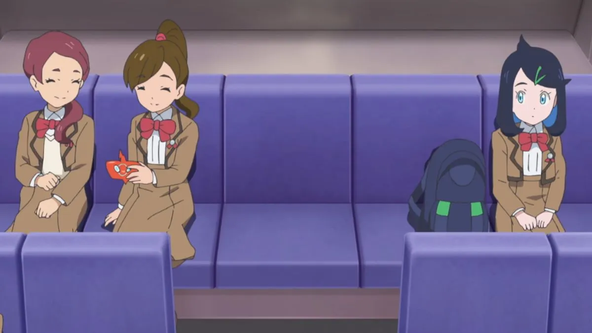 Liko from Pokemon Horizons the Series sitting on a bus next to two classmates, all in school uniform