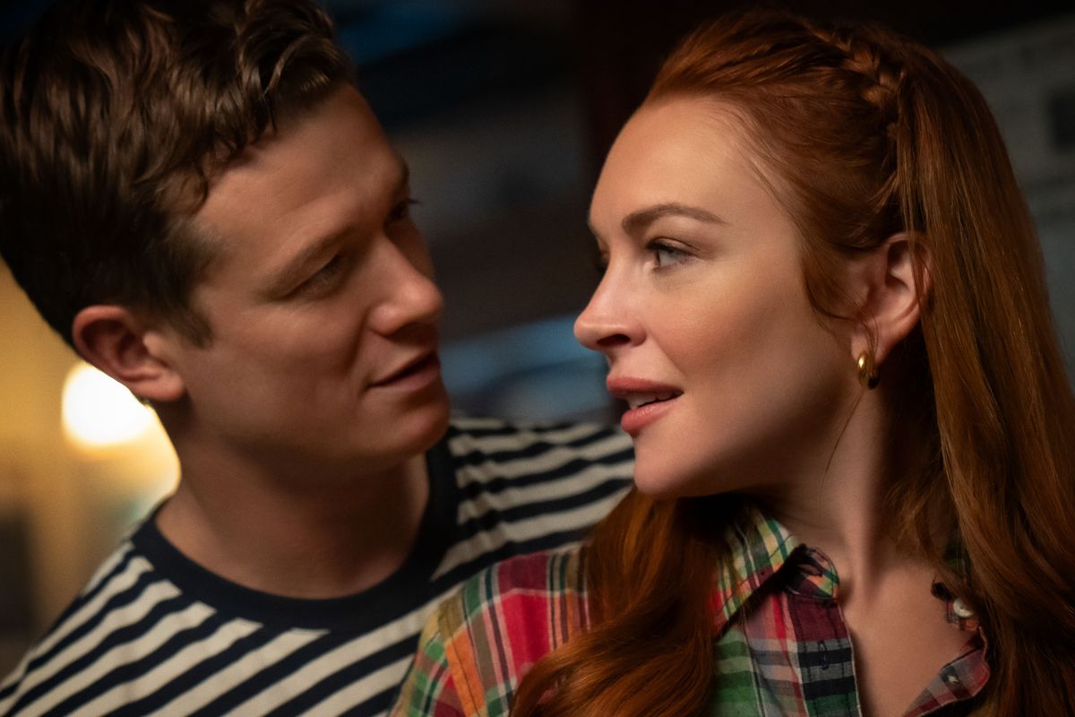 Ed Speelers montre à Lindsey Lohan comment jouer aux fléchettes.  Les deux se regardent avec envie dans les yeux