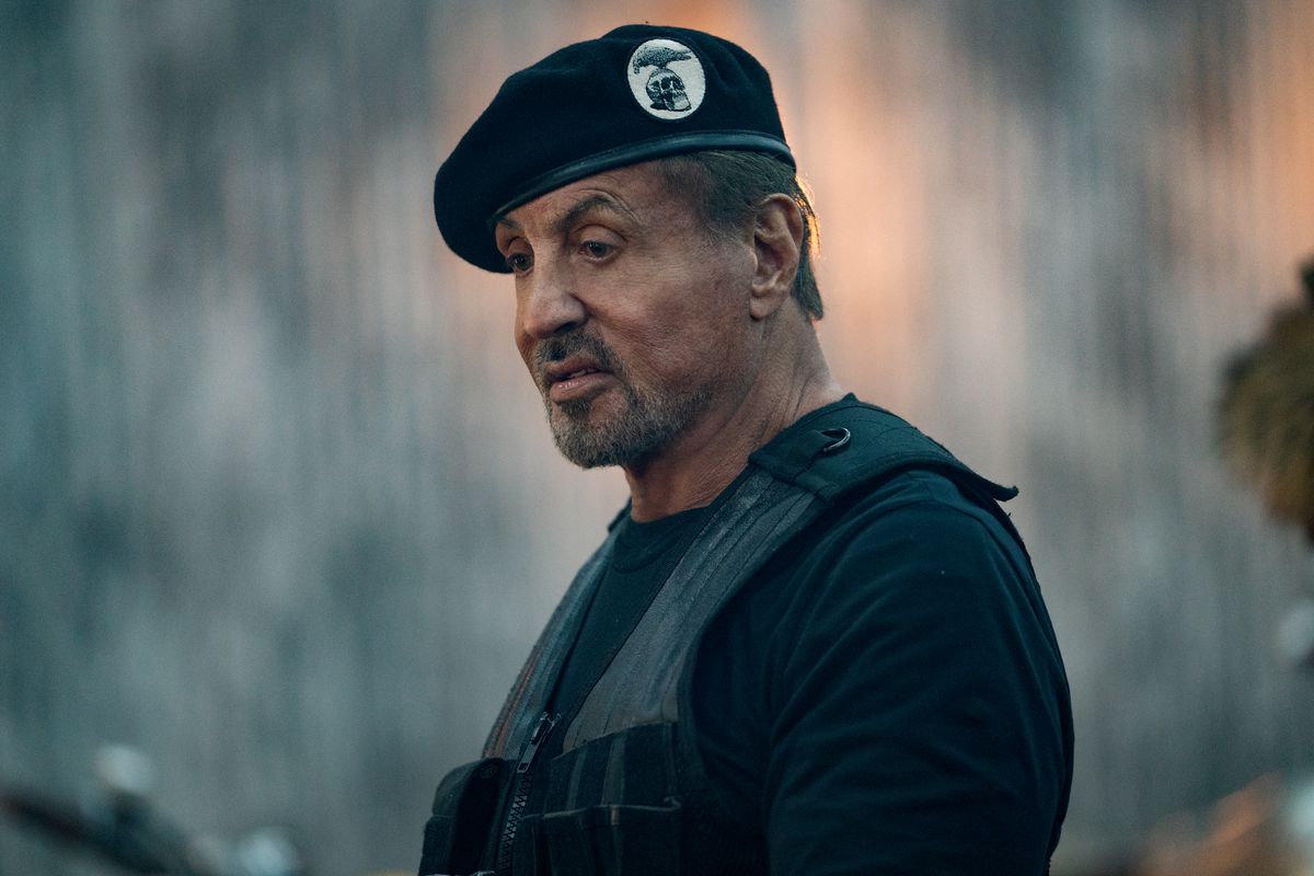 Un plan médian de Sylvester Stallone portant un béret et un gilet noirs dans le film Expend4bles.