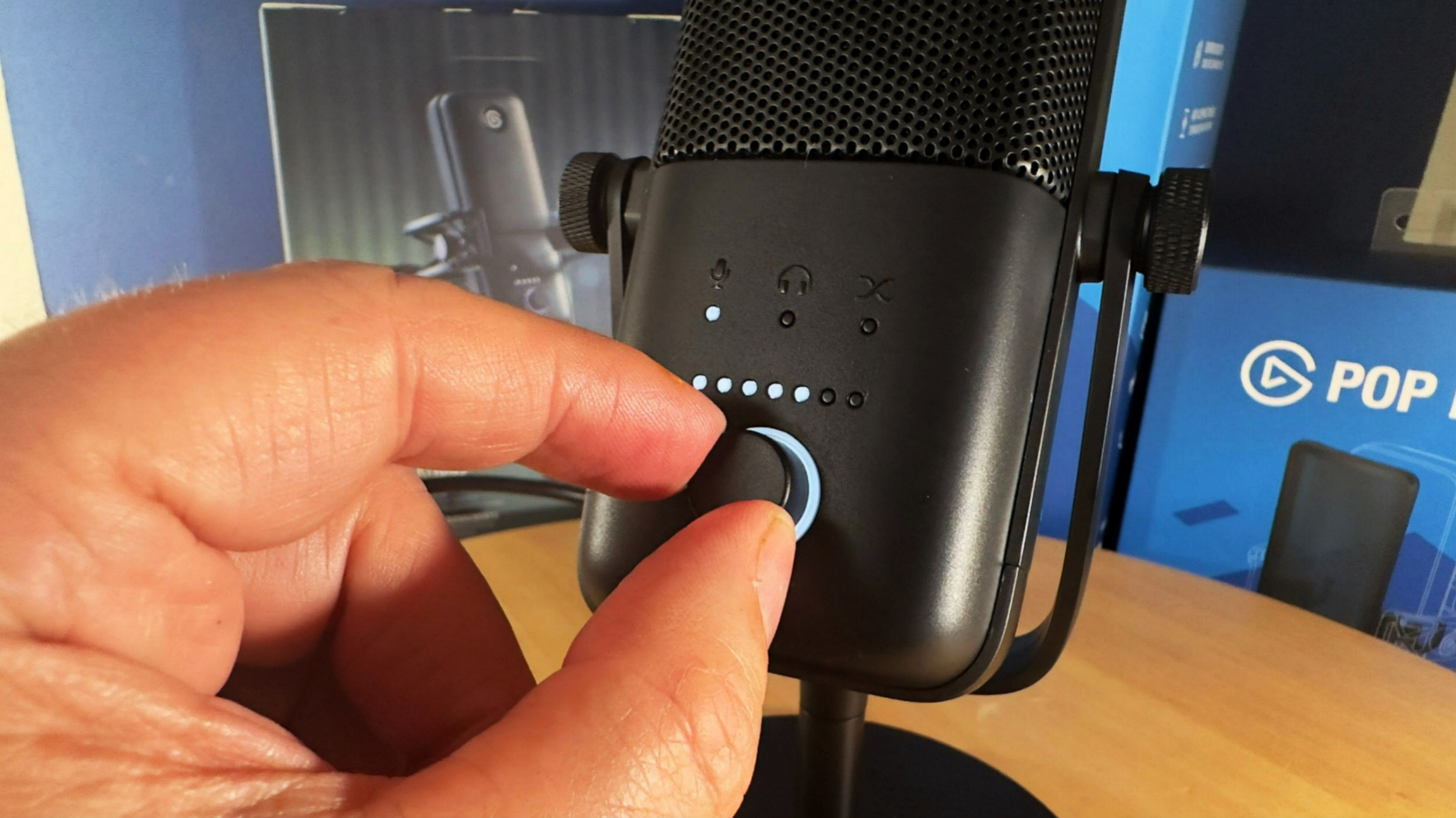 Elgato Wave : 3 examine l'image montrant quelqu'un ajustant une molette sur le microphone.