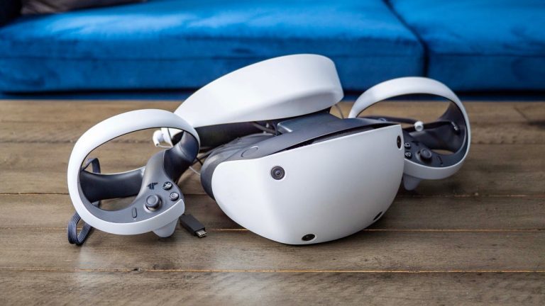 Sony PSVR 2 VR headset sitting on a wood table with a blue sofa behind it.