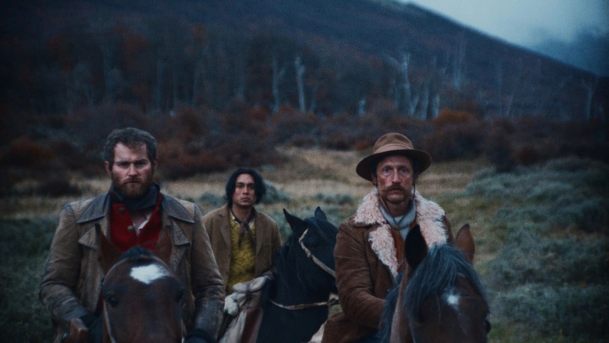 Trois hommes à l'air sévère montés à cheval avec une forêt d'arbres et de buissons au loin.