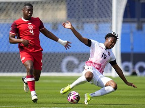 Le défenseur canadien Kamal Miller (4) travaille contre le milieu de terrain de Trinité-et-Tobago Ajani Fortune