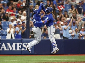 Justin Turner des Blue Jays de Toronto célèbre avec l'entraîneur du troisième but Carlos Febles.