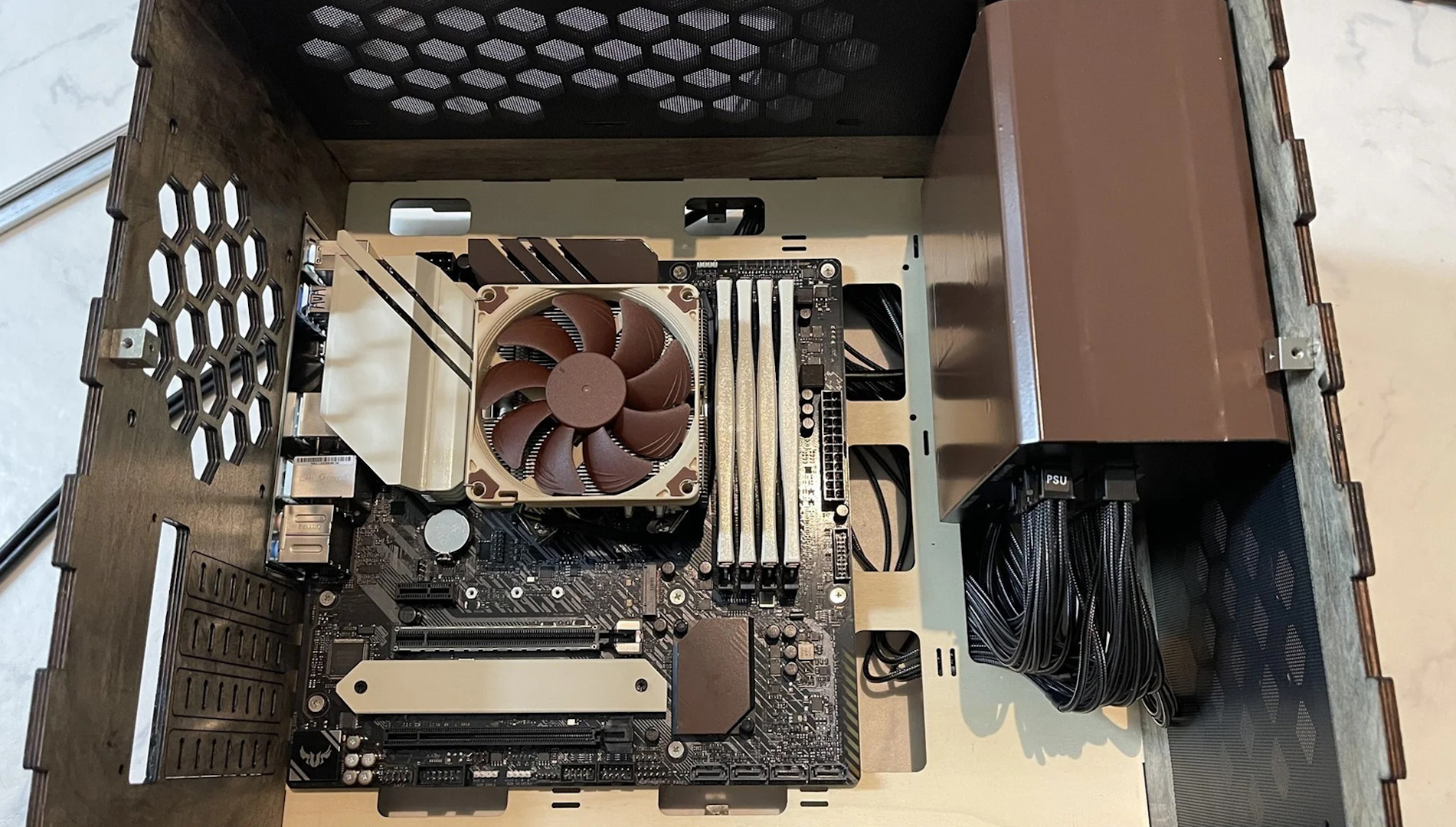 L'intérieur du PC gamer Noctua en bois avec carte mère et carénage d'alimentation peints