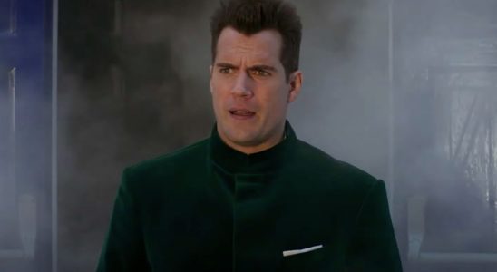 Henry Cavill walks out of smoke in a green velvet jacket in Argylle.