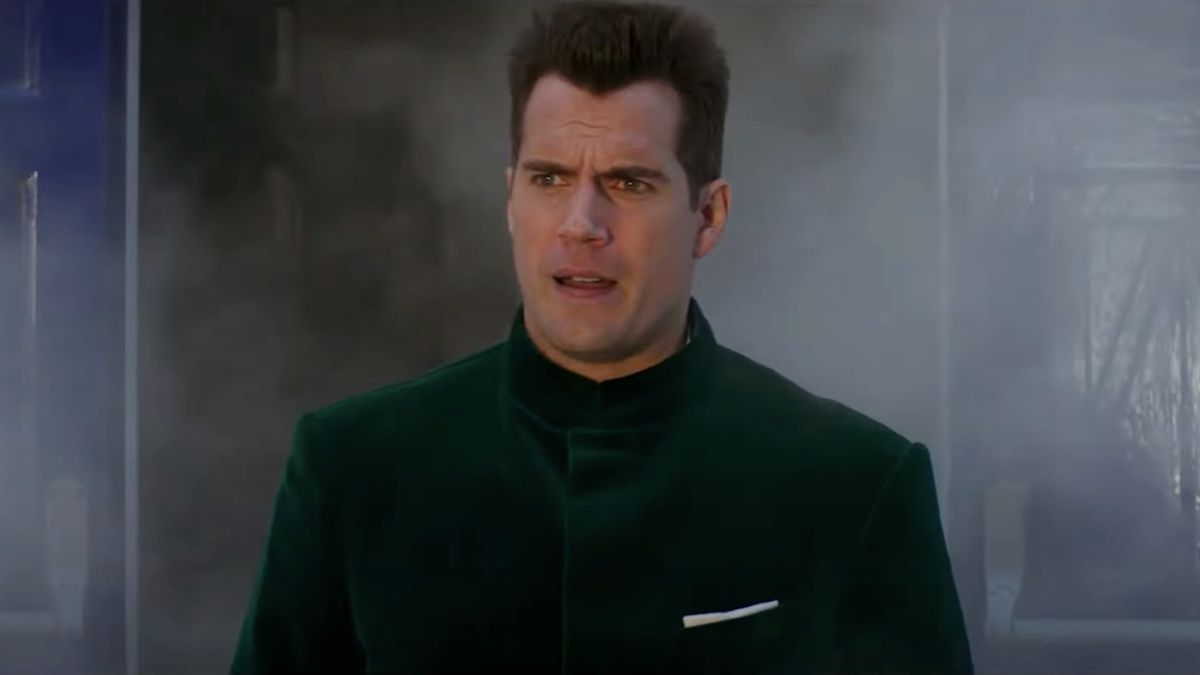 Henry Cavill walks out of smoke in a green velvet jacket in Argylle.