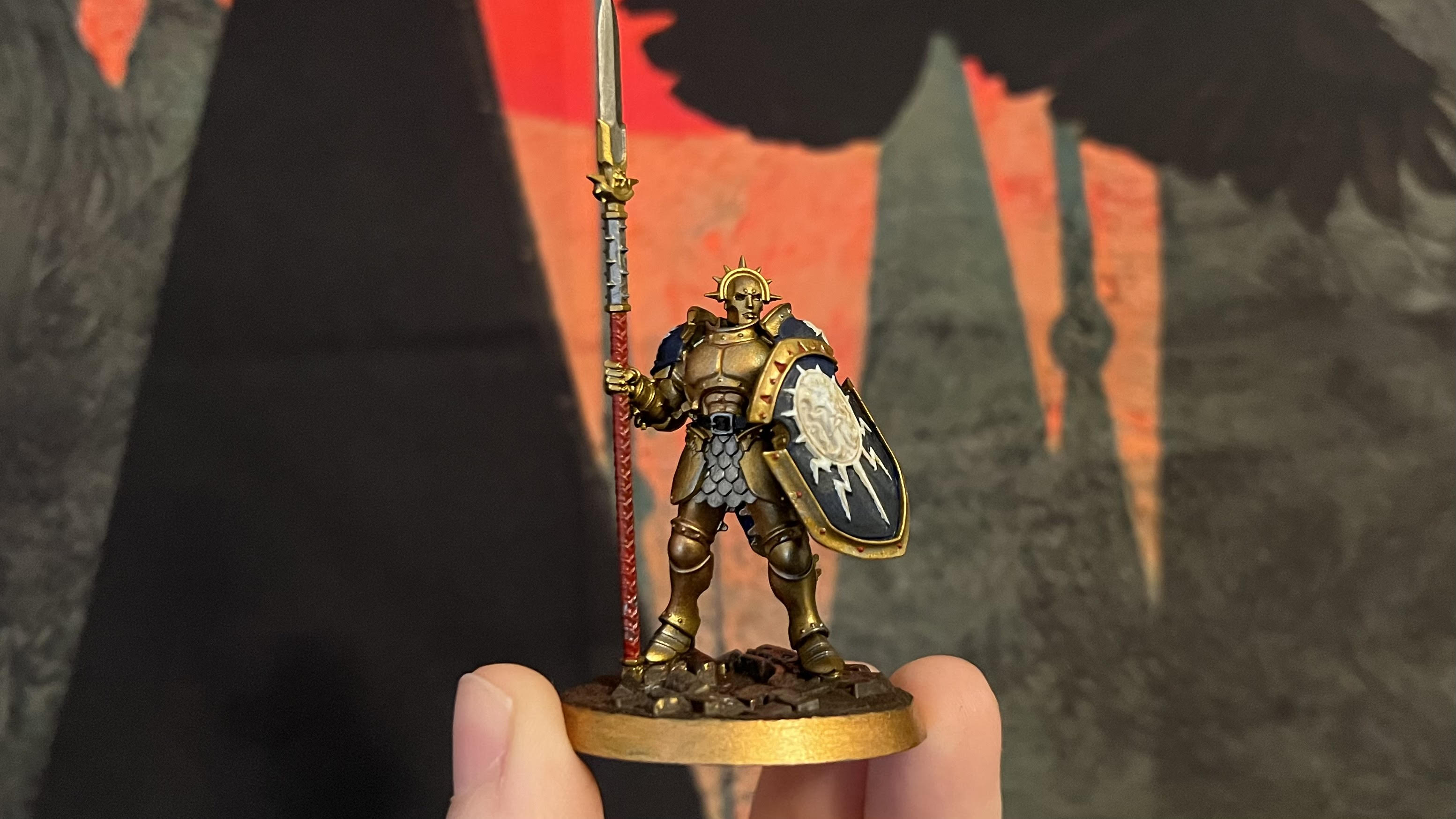 Peint Stormcast Eternal Vindictor mini.  Il a une armure dorée et un bouclier bleu et blanc