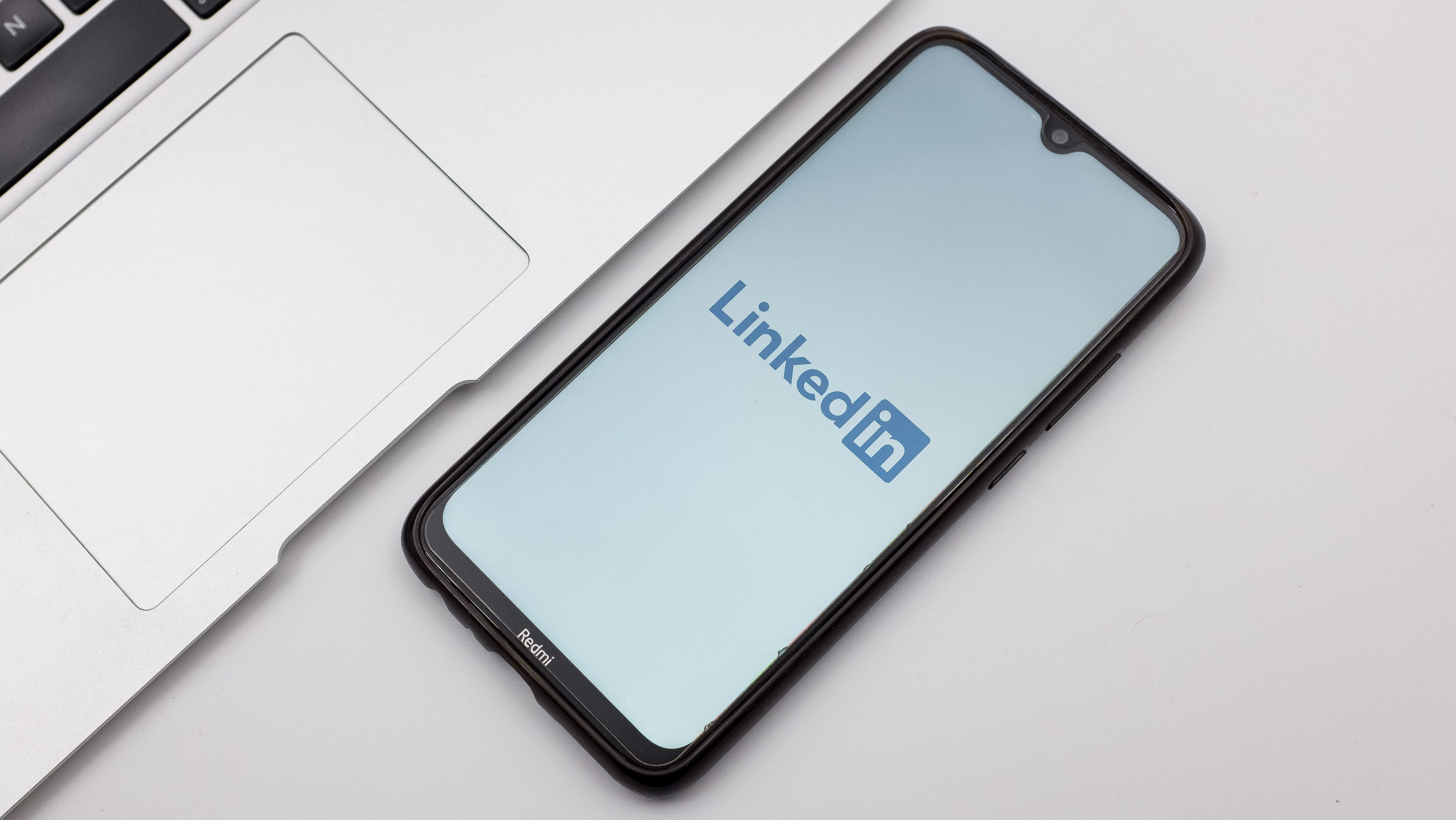 Application mobile LinkedIn affichée sur un smartphone posé sur un bureau