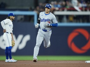 Le frappeur désigné des Dodgers de Los Angeles Shohei Ohtani contourne les buts devant l'arrêt-court des Blue Jays Bo Bichette après avoir frappé un circuit en solo lors de la première manche à Toronto le vendredi 26 avril 2024.