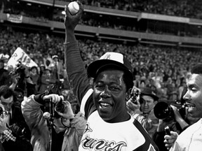 Hank Aaron tient en l'air le ballon qu'il a frappé pour son 715e circuit en carrière.