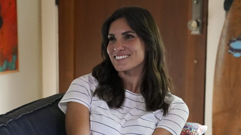 Kensi smiling on couch in striped shirt on NCIS: Los Angeles