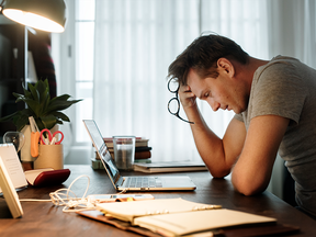 Un jeune homme triste assis devant son ordinateur