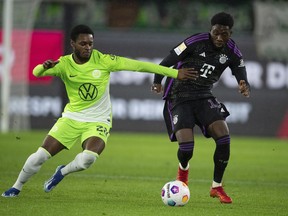 Ridle Baku de Wolfsburg, à gauche, et Alphonso Davies du Bayern se battent pour le ballon lors du match de football de la Bundesliga allemande entre VfL Wolfsburg et le Bayern Munich à la Volkswagen Arena, Wolfsburg, Allemagne, le mercredi 20 décembre 2023. Comptez les Whitecaps de Vancouver parmi ceux qui regardent Alphonso avenir avec le Bayern Munich avec intérêt.  Les Whitecaps bénéficieront de toute vente future, grâce à une clause de revente négociée lors de la vente de la star canadienne à la centrale allemande en juillet 2018.