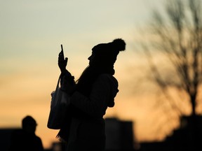 Une personne se découpant sur le ciel du soir prend une photo avec un smartphone à Philadelphie, le jeudi 12 décembre 2019.