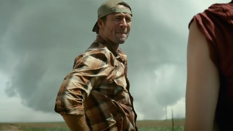 Glen Powell in the trailer for Twisters with a tornado behind him.