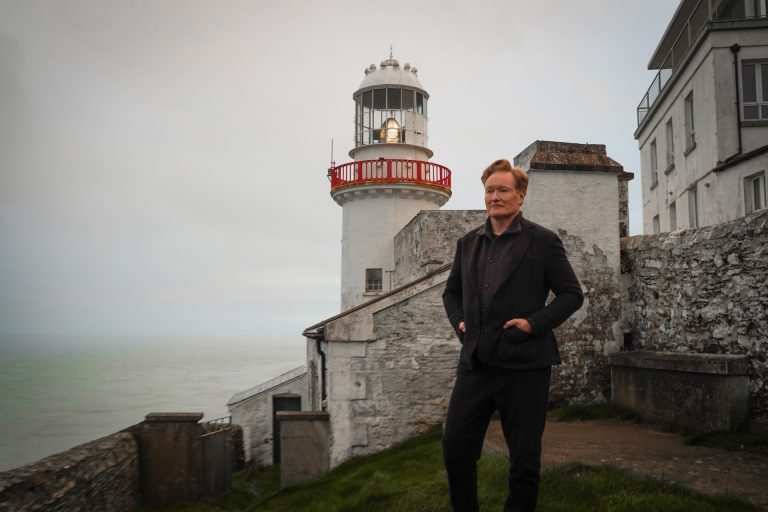 Conan O'Brien stands in front of a lighthouse in Conan O'Brien Must Go