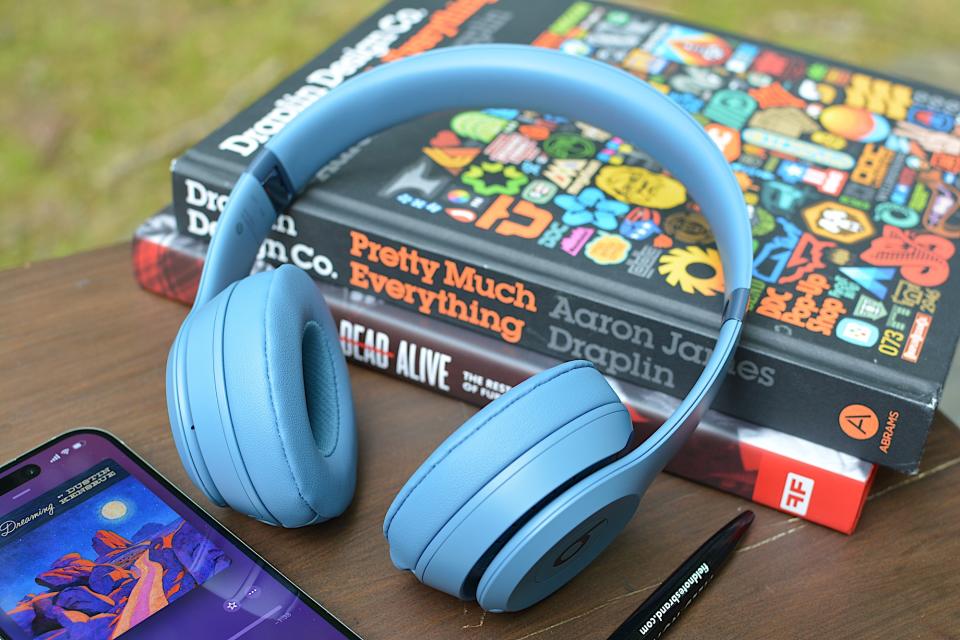 Beats Solo 4 posé sur deux livres avec un iPhone à gauche et un stylo noir au premier plan. 