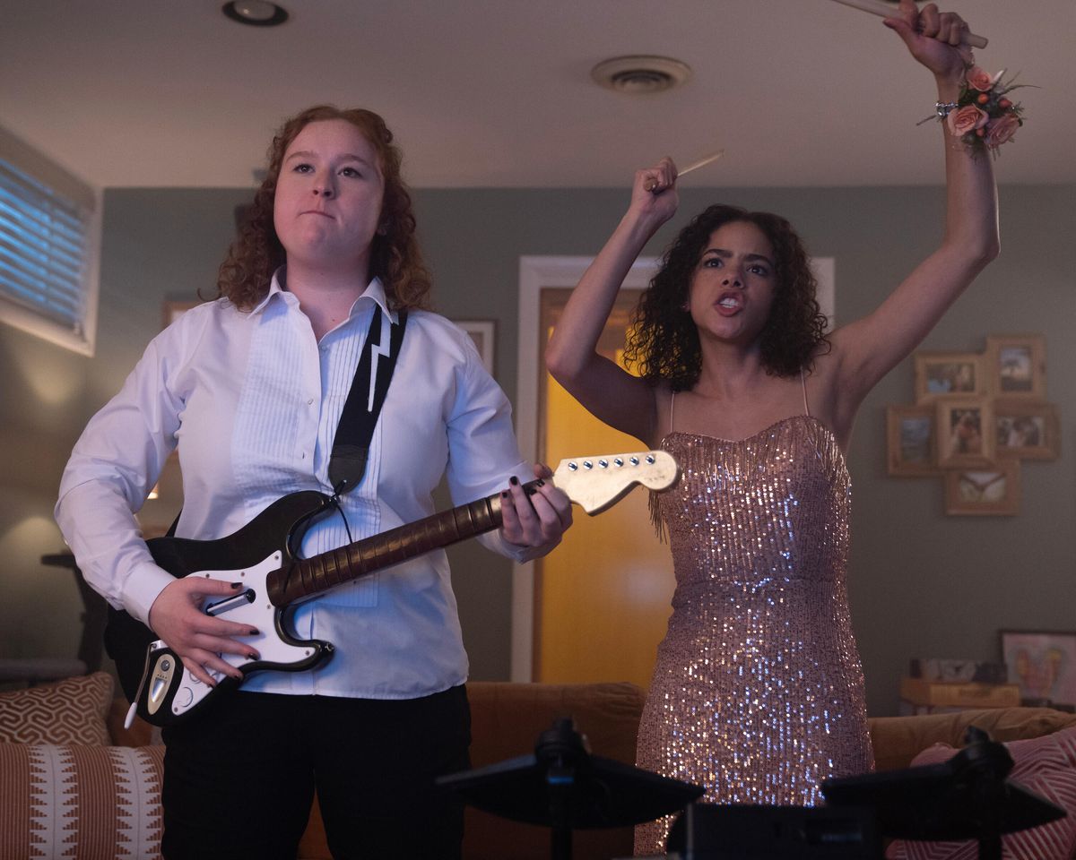 Deux filles en tenue de bal jouant avec une guitare en plastique et des baguettes de tambour lors des Prom Dates.