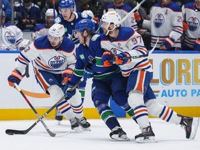 Connor McDavid des Oilers d'Edmonton, à droite, vérifie Brock Boeser des Canucks de Vancouver tandis que Mattias Janmark d'Edmonton, à l'arrière gauche, regarde pendant la première période du premier match d'une série éliminatoire de deuxième tour de la Coupe Stanley de hockey de la LNH à Vancouver le mercredi 8 mai 2024. .