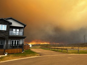 Une maison avec un feu de forêt en arrière-plan.