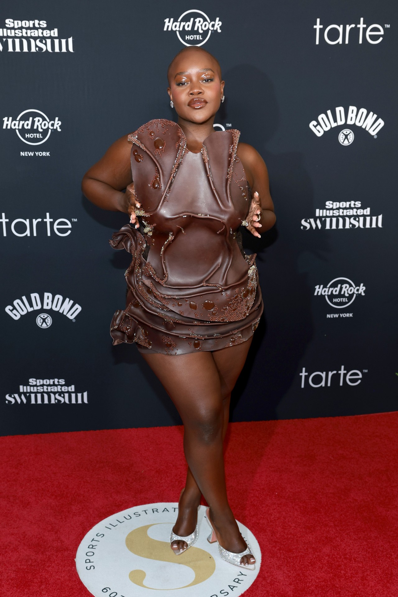 Achieng Agutu portant une robe marron qui semble faite d'eau lors de la sortie du numéro 2024 de Sports Illustrated et de la célébration du 60e anniversaire au Hard Rock Hotel New York.