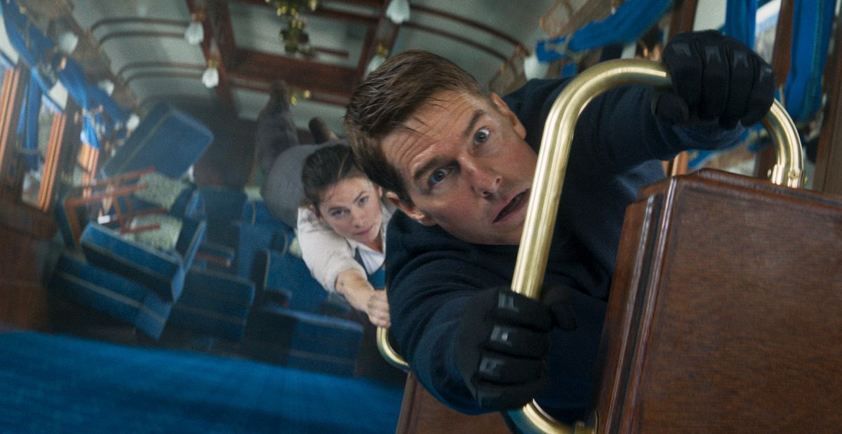 Tom Cruise dans le rôle d'Ethan Hunt s'accroche à une balustrade dans un wagon tourné à la verticale alors que Hayley Atwell s'accroche à lui dans Mission : Impossible – Dead Reckoning Part One