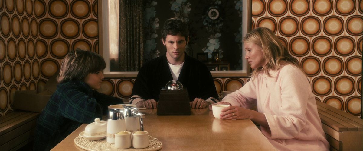 Cameron Diaz, James Marsden et Sam Oz Stone sont assis autour de leur table à manger et regardent tous la boîte de The Box.