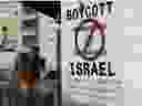 Un touriste photographie une pancarte peinte sur un mur de la ville biblique de Bethléem, en Cisjordanie, le 5 juin 2015, appelant au boycott des produits israéliens provenant des colonies juives.  La campagne internationale BDS (boycott, désinvestissement et sanctions), qui prône l'interdiction des produits israéliens, vise à exercer une pression politique et économique sur l'occupation des territoires palestiniens par Israël dans le but de répéter le succès de la campagne qui a mis fin à l'apartheid dans le Sud. Afrique. 