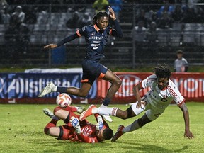 Le gardien du CS Saint-Laurent Konstantinos Maniatis, en bas à gauche, arrête l'attaquant du Toronto FC Deandre Kerr, à droite, alors que Cedrick Adamou de Saint-Laurent défend lors du quart de finale de football de la deuxième mi-temps du Championnat canadien à Montréal, le mercredi 8 mai 2024.