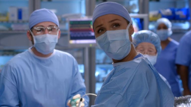 Camilla Luddington looks up while wearing scrubs in the operating room on Grey