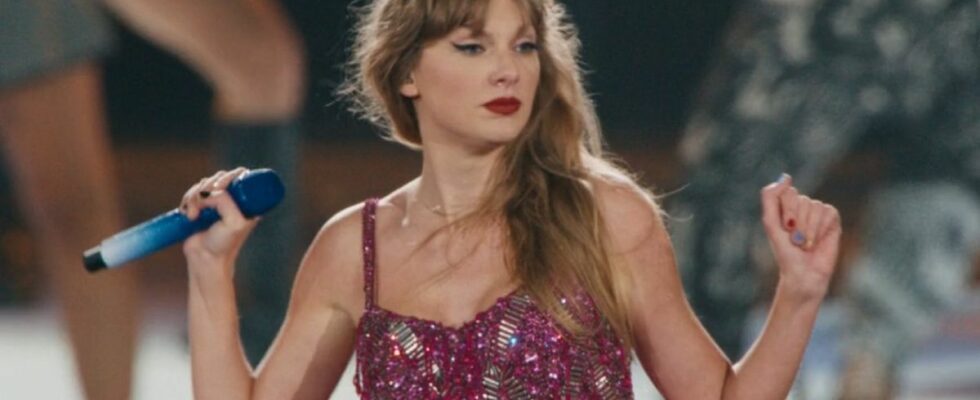 Taylor Swift wearing a pink set, holding both her arms up and out to the side looking kind of sassy.