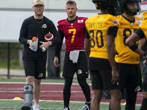 Le quart-arrière des Tiger-Cats de Hamilton Bo Levi Mitchell (à gauche) s'entretient avec le quart-arrière Taylor Powell (7) lors de la première journée du camp d'entraînement au stade Ron Joyce de l'Université McMaster à Hamilton, le dimanche 12 mai 2024.