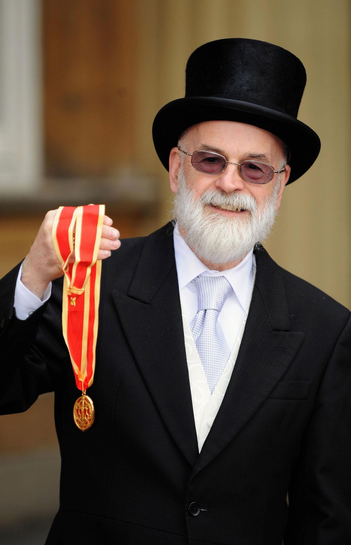 Sir Terry Pratchett montre son prix de chevalerie devant le palais de Buckingham.