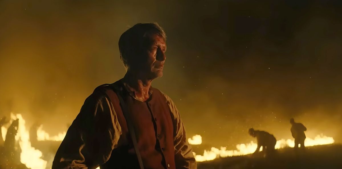 Mads Mikkelsen debout devant un paysage en feu