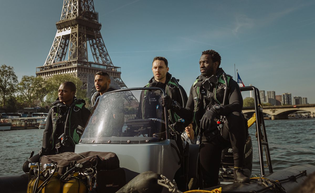 Un groupe de policiers de la Brigade Fluviale descendent une vedette sur la Seine devant la Tour Eiffel dans le thriller Netflix sur les requins de Xavier Gens, Under Paris.