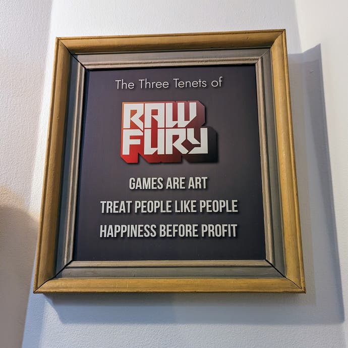 Une photographie montrant une affiche encadrée sur un mur qui énonce les trois principes de Raw Fury.  Ce sont les suivants : les jeux sont de l'art, ils traitent les gens comme des gens et le bonheur avant le profit.