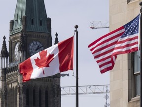 Des drapeaux canadiens et américains flottent près de la Colline du Parlement, le mercredi 22 mars 2023, à Ottawa.