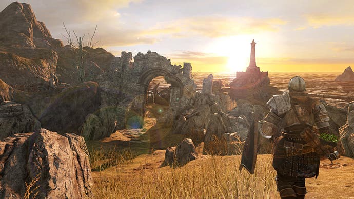 Une scène de coucher de soleil dans Dark Souls 2, alors que le personnage du joueur vêtu d'une armure regarde l'horizon derrière une scène de rochers imposants.