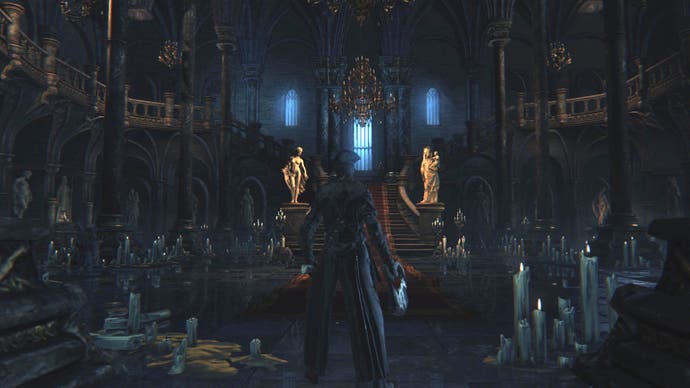 Un personnage joueur de Bloodborne se tient dans une grande pièce à l’intérieur d’un château gothique orné.  L'endroit est jonché de bougies qui ne diffusent pas beaucoup de lumière.