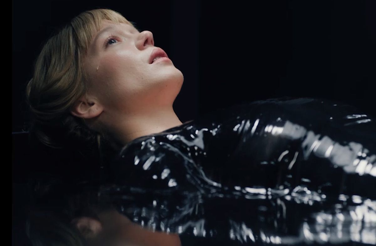 Gabrielle (Léa Seydoux), une jeune femme pâle vêtue de vinyle noir, est allongée sur le dos, le regard tourné vers le haut, une larme coulant sur sa joue dans La Bête