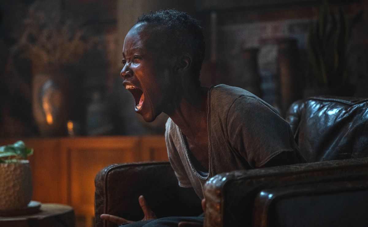 Sam (Lupita Nyong'o), assise dans un grand fauteuil en cuir dans une pièce sombre, ferme les yeux et crie dans A Quiet Place: Day One de Michael Sarnoski.