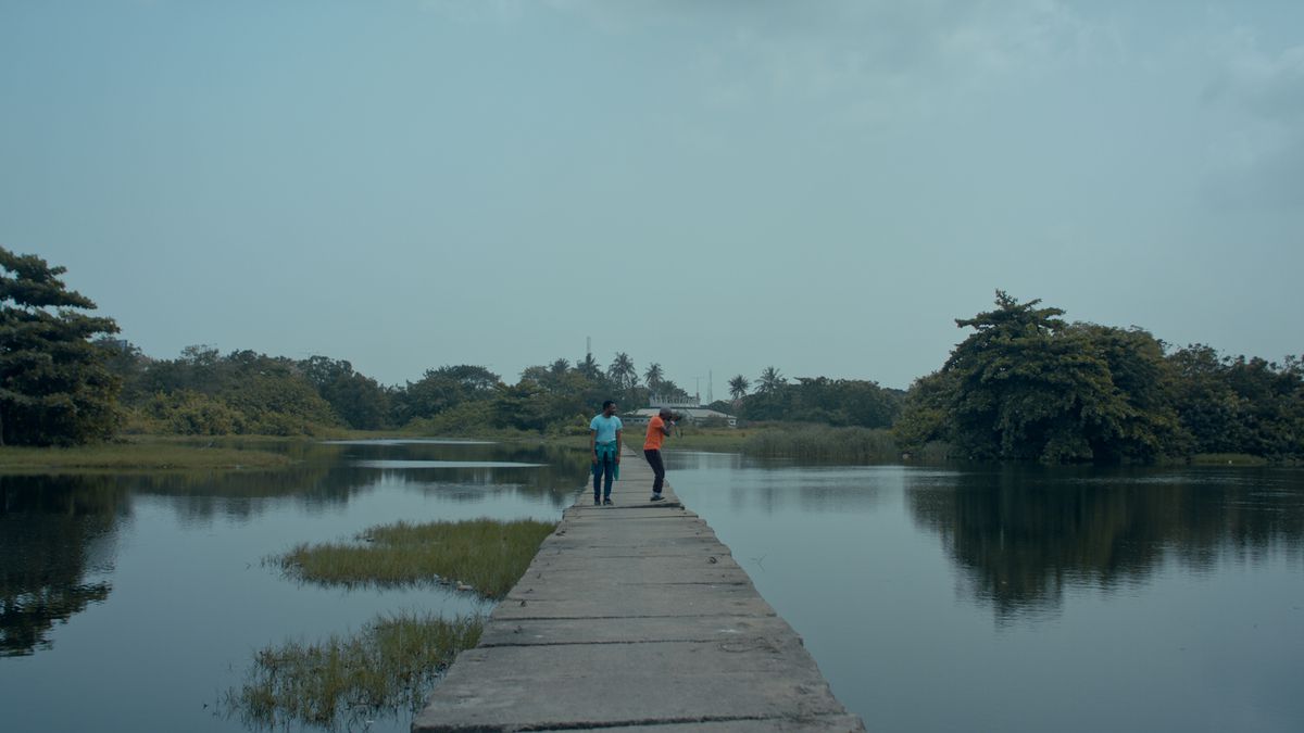 Deux garçons se tiennent debout sur un pont, regardant l'eau, dans Toutes les couleurs du monde sont entre noir et blanc