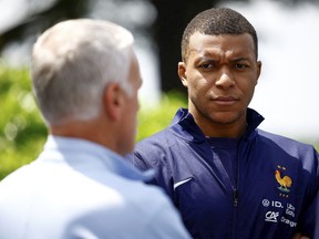 Le footballeur français Kylian Mbappe, à droite, écoute l'entraîneur-chef Didier Deschamps au centre d'entraînement de l'équipe nationale de football à Clairefontaine.